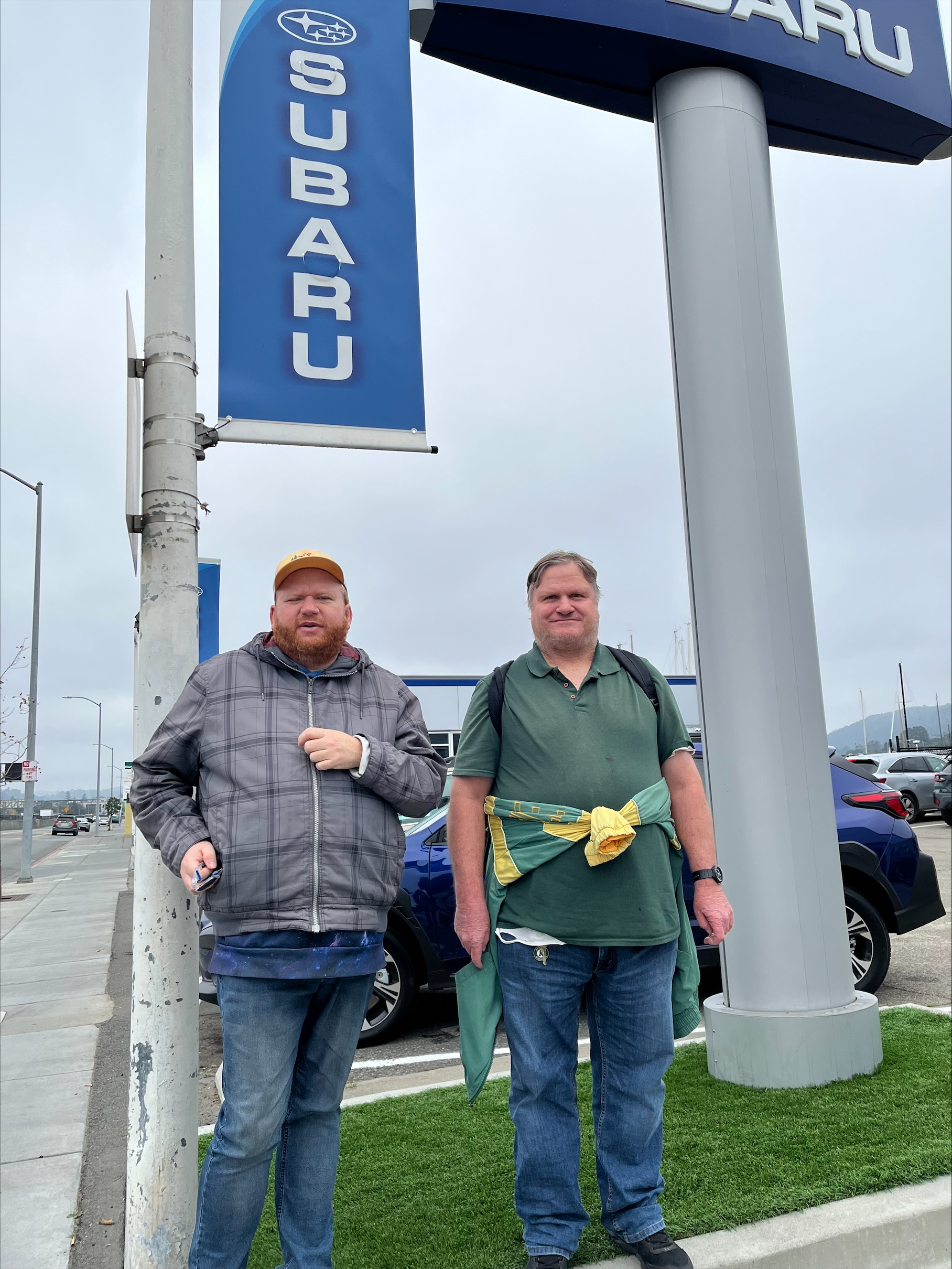 Two man standing in front of Subaru
